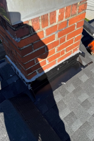 Close up view of newly installed custom step flashing and counter flashing chimney repair along a shingle roof line on a home near Island Station