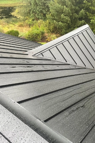 Finished charcoal gray standing seam metal roofing installed on a steep slope residential estate in Rosemont.
