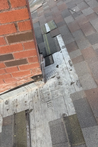 Detailed view of newly installed custom metal chimney flashing and counter flashing on a weathered shingle roof line in Bolton.